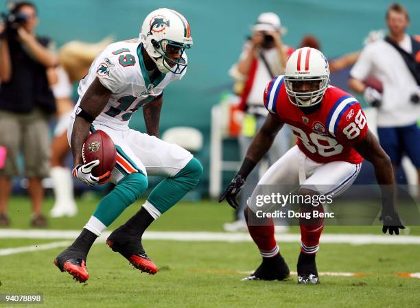 Wide receiver Ted Ginn Jr. #19 of the Miami Dolphins looks to avoid a tackle attempt by Sam Aiken of the New England Patriots at Land Shark Stadium...