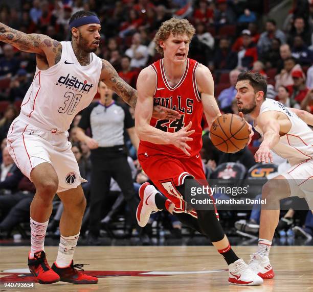 Lauri Markkanen of the Chicago Bulls drives between Mike Scott and Tomas Satoransky of the Washington Wizards at the United Center on April 1, 2018...