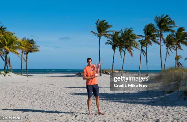 John Isner of the USA poses on Crandon Park Beach with the trophy after beating Alexander Zverev of Germany 6-7 6-4 6-4 in the men's final on Day 14...