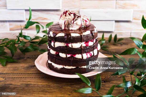 homemade chocolate cake called black forest cake with mascarpone cream and cherry topped with sweet meringues on a plate on a wooden table, selective focus - black forest gateau stock-fotos und bilder
