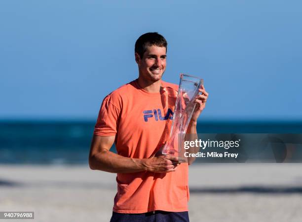 John Isner of the USA poses on Crandon Park Beach with the trophy after beating Alexander Zverev of Germany 6-7 6-4 6-4 in the men's final on Day 14...