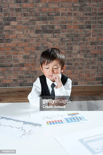 boy wearing suit looking over documents - children looking graph stock pictures, royalty-free photos & images