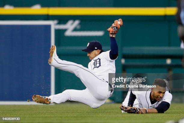 Shortstop Jose Iglesias of the Detroit Tigers falls to the ground after colliding with left fielder Victor Reyes of the Detroit Tigers after catching...