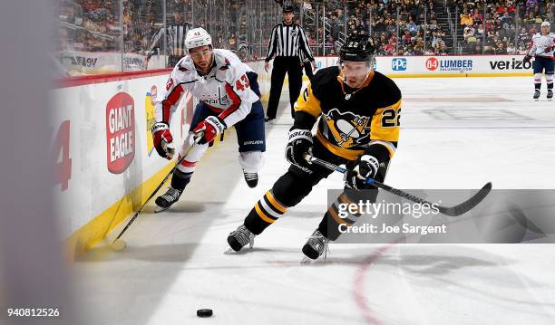 Matt Hunwick of the Pittsburgh Penguins and Tom Wilson of the Washington Capitals skate for the puck at PPG Paints Arena on April 1, 2018 in...