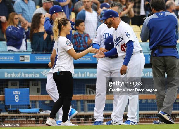 Olympic gold medalist snowboarder Chloe Kim shakes hands with coach Chris Woodward of the Los Angeles Dodgers after the singing of the National...