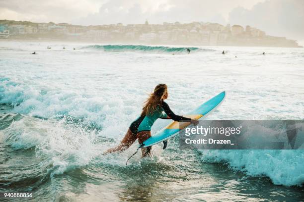 internaute femme saute sur sa planche de surf dans les vagues - sydney australia photos et images de collection