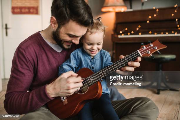 daughter and father playing guitars - ukelele stock pictures, royalty-free photos & images