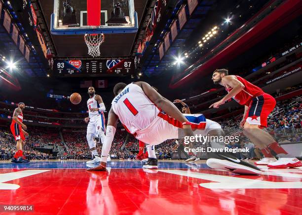 Reggie Jackson of the Detroit Pistons gets up off the court after making a basket in front of teammate Andre Drummond and next to Tomas Satoransky of...