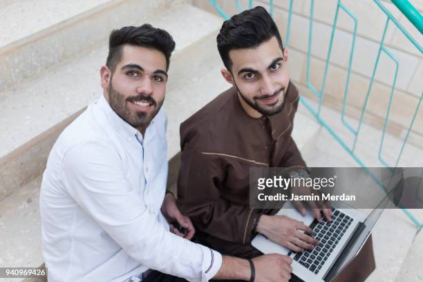 arab young adults using laptop - emirati guy using laptop stock-fotos und bilder