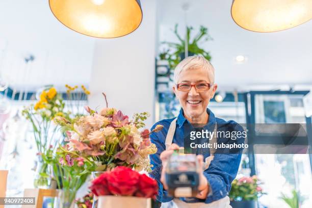 mature woman working in florist shop - debit cards credit cards accepted stock pictures, royalty-free photos & images