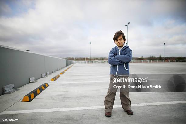 boy stands in car park - kids standing crossed arms stock-fotos und bilder
