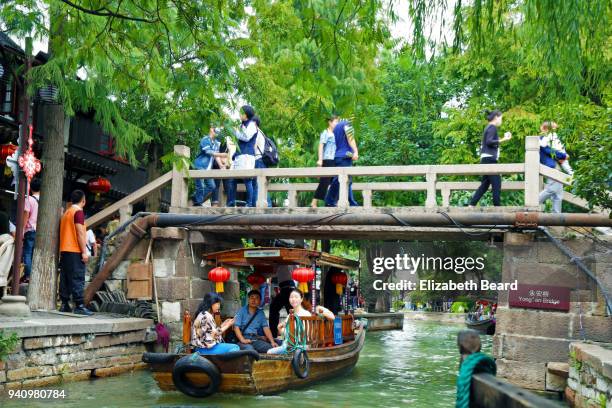 sampan being rowed under a bridge zhujiajiao water town, shanghai - zhujiajiao stock pictures, royalty-free photos & images