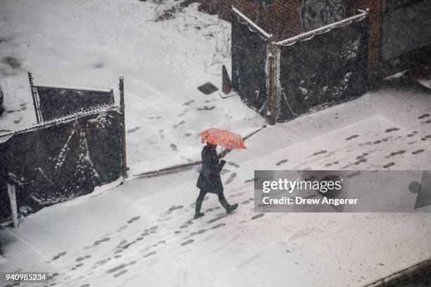 Woman carries an umbrella as she walks through the snow on Atlantic Avenue, April 2, 2018 in the Brooklyn borough of New York City. One day after a...