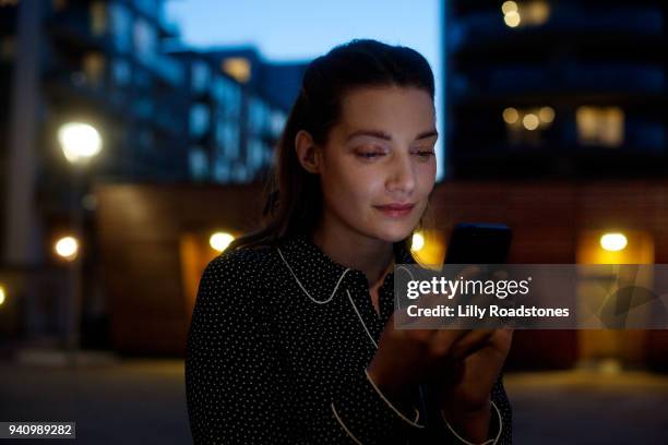 woman using mobile phone at night - lilly roadstones stock pictures, royalty-free photos & images