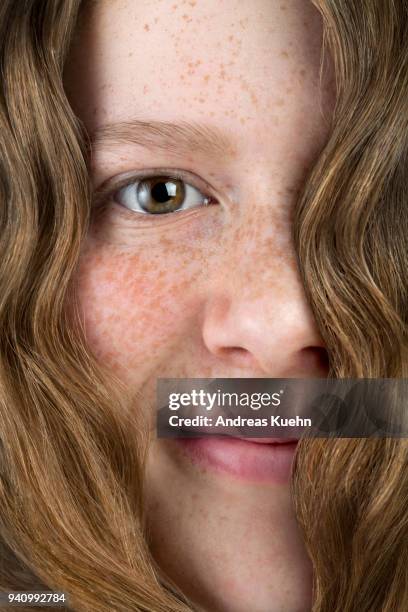 smiling sixteen year old teenage girl with pale skin, freckles and one eye covered with her wavy hair, close up. - pale complexion fotografías e imágenes de stock