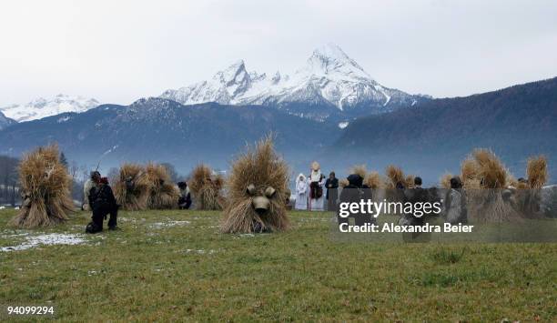 Traditional Bavarian dressed men, known as Buttenmandl and Krampusse, pray during the Saint Nicolas parade in front of the Watzmann mountain on...