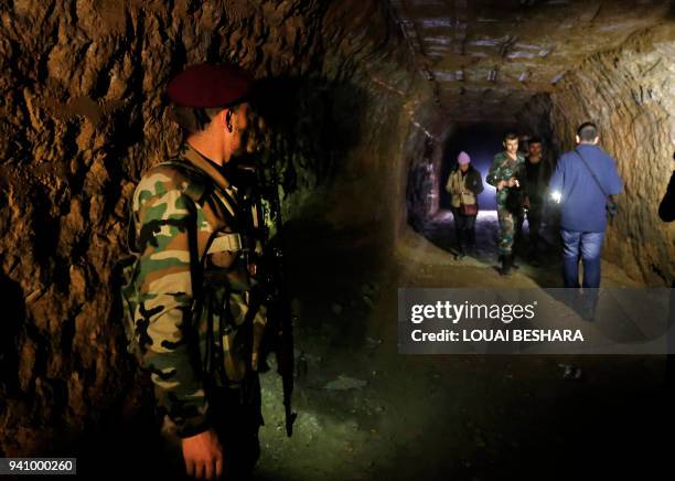 Syrian journalists and regime members are seen inside a tunnel previously used by rebel-fighter for smuggling goods and taking shelter, in Jobar in...