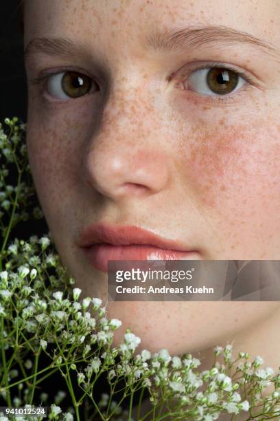 close up portrait of a sixteen year old teenage girl with a soft smile, freckles and pale complextion holding white wildflowers. - smile close up stock-fotos und bilder