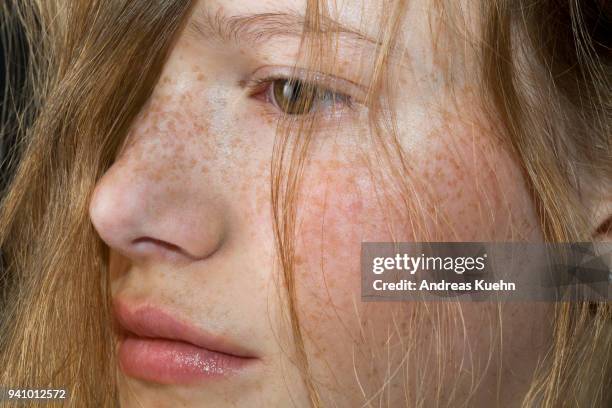 close up shot of a teenage girl in a profile postion with pale skin, freckles and strands of hair coming down her cheek. - pale complexion stock-fotos und bilder