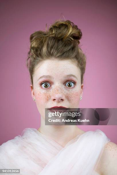 portrait of a sixteen year old teenage girl with an updo, pale skin, freckles and big eyes in front of a purple colored background. - pale complexion fotografías e imágenes de stock