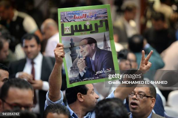 An Egyptian man carries a copy of a newspaper, bearing the portrait of Egyptian President Abdel Fattah al-Sisi, during a press conference by the...