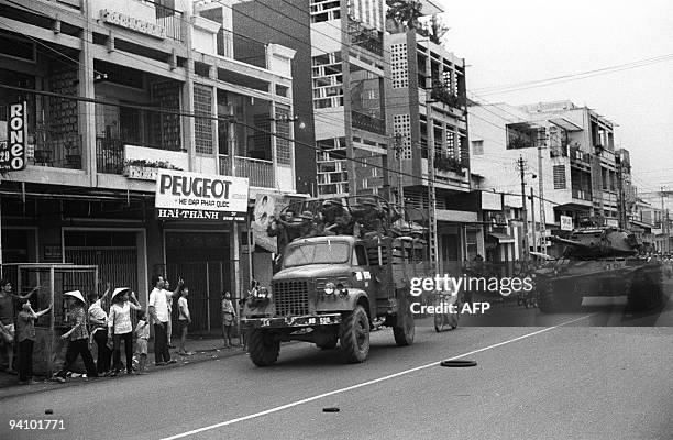 Photo taken 27 May 1975 shows Vietnamese soldiers of the National Liberation Forces being saluted by inhabitants of Saigon, after the fall of the...