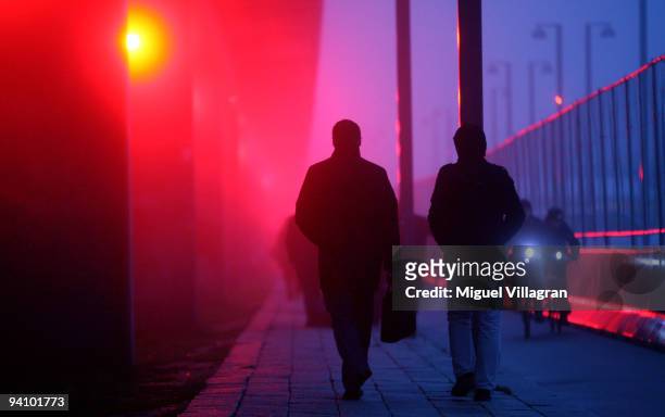 Participants of the United Nations Climate Change Conference walk past a bridge that is illuminated with red light next to the Bella Center on...