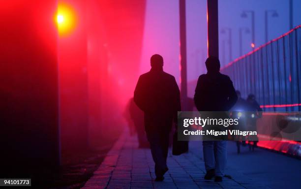 Participants of the United Nations Climate Change Conference walk past a bridge that is illuminated with red light next to the Bella Center on...