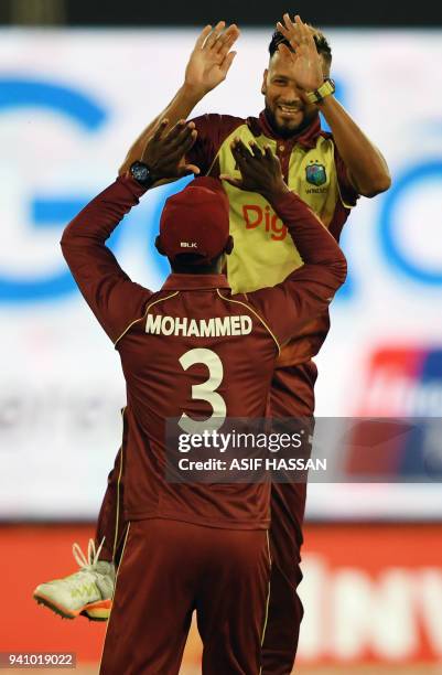 West Indies bowler Rayad Emrit celebrates with team captain Jason Mohammed after taking the wicket of Pakistani batsman Fakhar Zaman during the...