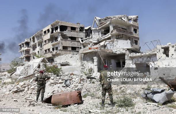 Syrian regime members are seen standing amid the destruction in the previously rebel-held Jobar in Eastern Ghouta on April 2, 2018. Syria's regime...