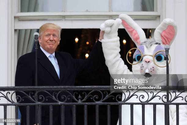 President Donald Trump lifts the hand of a person in an Easter Bunny costume on the Truman Balcony during the 140th annual Easter Egg Roll on the...