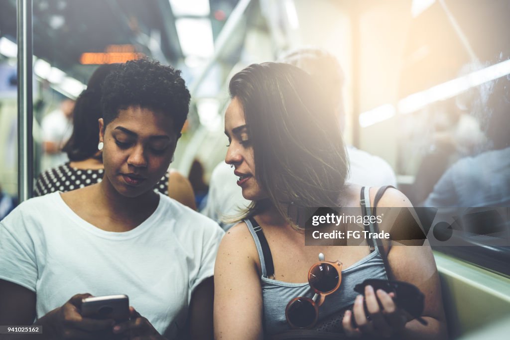 Lesbian Couple Using Mobile at Subway