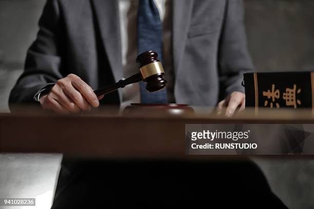 lawyer holding gavel at desk - auction table stock pictures, royalty-free photos & images