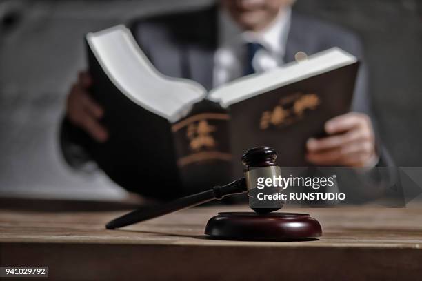 lawyer reading law book at desk - law books fotografías e imágenes de stock