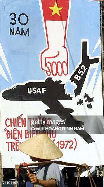 Hanoi street vendor walks past a poster depicting the Vietnamese victory over US Airforce B52 massive bombing campaign launched against the...