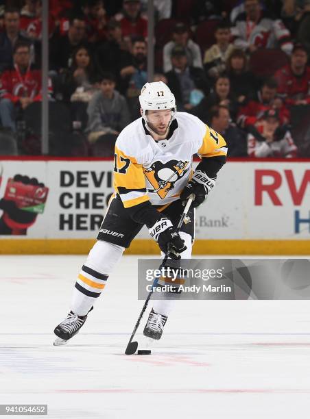 Bryan Rust of the Pittsburgh Penguins plays the puck during the game against the New Jersey Devils at Prudential Center on March 29, 2018 in Newark,...