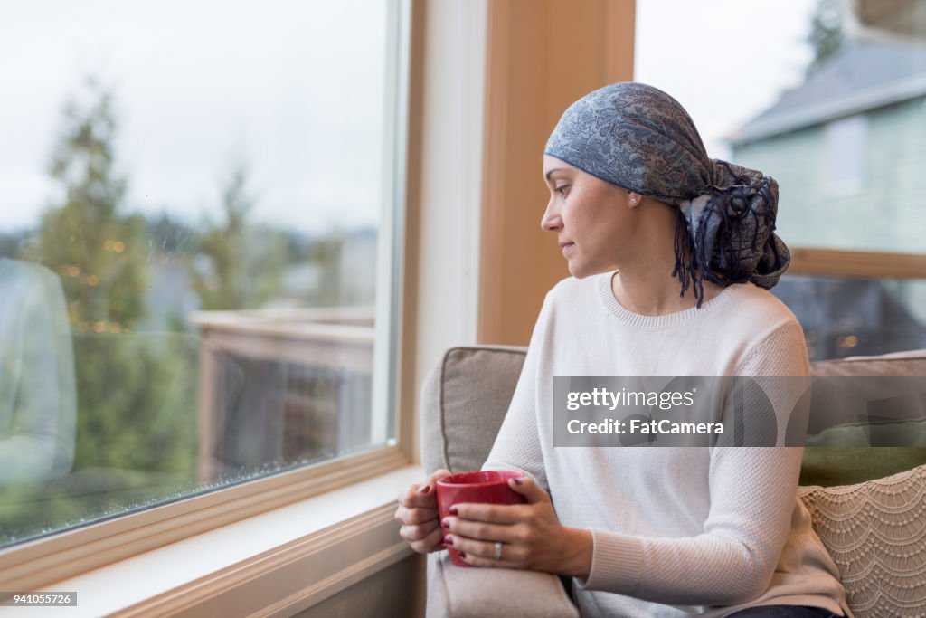Survivante d’un cancer ethniques d’âge mûr se trouve près de la fenêtre et se penche sur sa vie