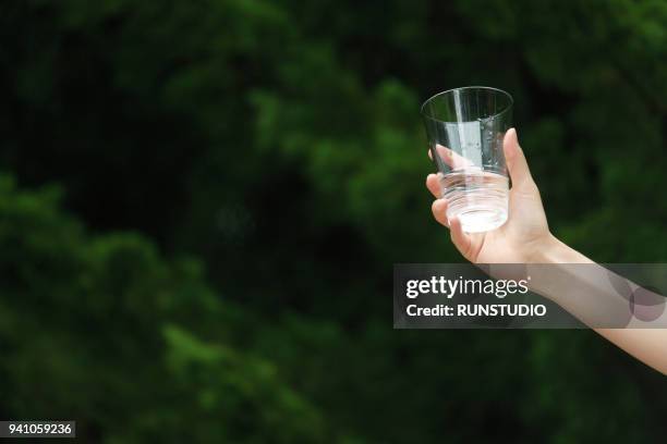 close up of woman holding glass of water - hand glasses stockfoto's en -beelden