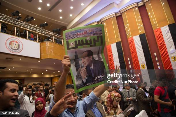 An Egyptian man carries a copy of a newspaper, bearing the portrait of Egyptian President Abdel Fattah al-Sisi, during a press conference by the...