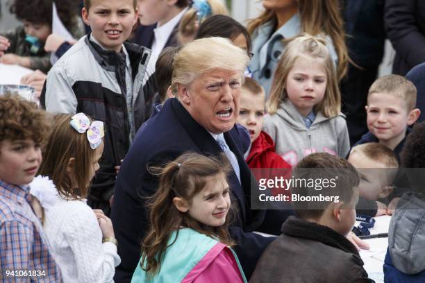 President Donald Trump, center, sits with children reading Easter cards from members of the military during the Easter Egg Roll on the South Lawn of...