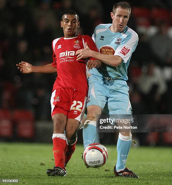 Theo Lewis of Cheltenham Town plays the ball under pressure from John Curtis of Northampton Town during the Coca Cola League Two Match between...