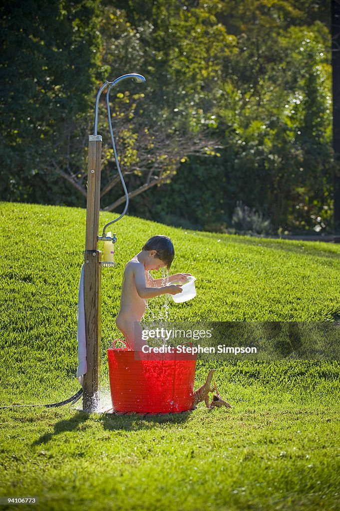 Small boy bathes in backyard shower