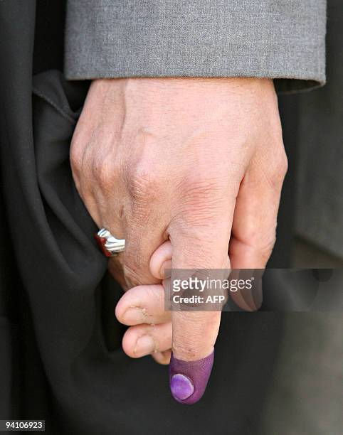 An Iraqi man with his finger stained with indelible ink holds the hand of his wife after voting in provincial elections in the southern city of...