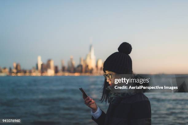 asian woman texting on the phone - jersey city stockfoto's en -beelden