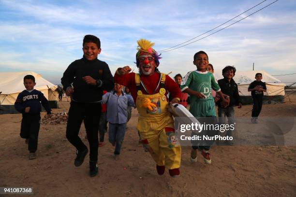 Palestinian clown entertains children on April 2, 2018 as they gather along the border with Israel east of Gaza City in support of Palestinian...