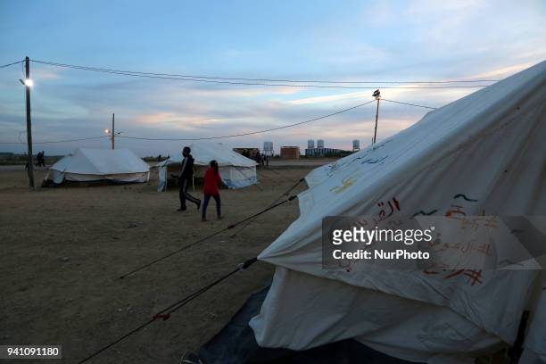 Palestinians walk next to tents on April 2, 2018 along the border with Israel east of Gaza City during a tent protest in support of Palestinian...