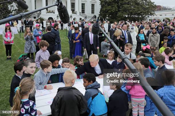 President Donald Trump, center, high fives a child while reading Easter cards from members of the military during the Easter Egg Roll on the South...