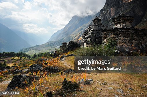 Buddhist chorten lined up along a footpath as the sun shines through the clouds in the Tsum Valley, Nepal Buddhist chorten lined up along a footpath as the sun shines through the clouds in the Tsum Valley, Nepal