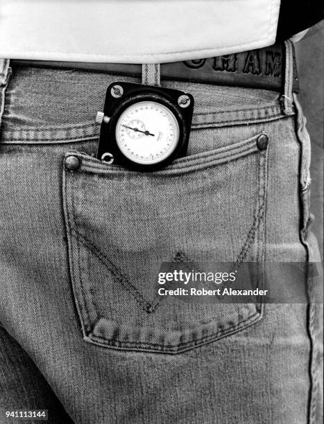 Member of NASCAR driver Dale Earnhardt Sr.'s racing team carries a stopwatch in his back pocket as he watches Earnhardt's car circle the track at...