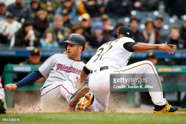 Joe Mauer of the Minnesota Twins slides in safe on a wild pitch against Edgar Santana of the Pittsburgh Pirates in the sixth inning during...